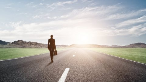 Woman walking toward the sunset on a wide, open road