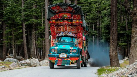 A highly-decorated lorry belches out fumes on a forest road
