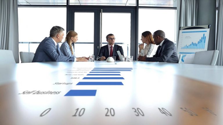 Executives at a conference table surrounded by data